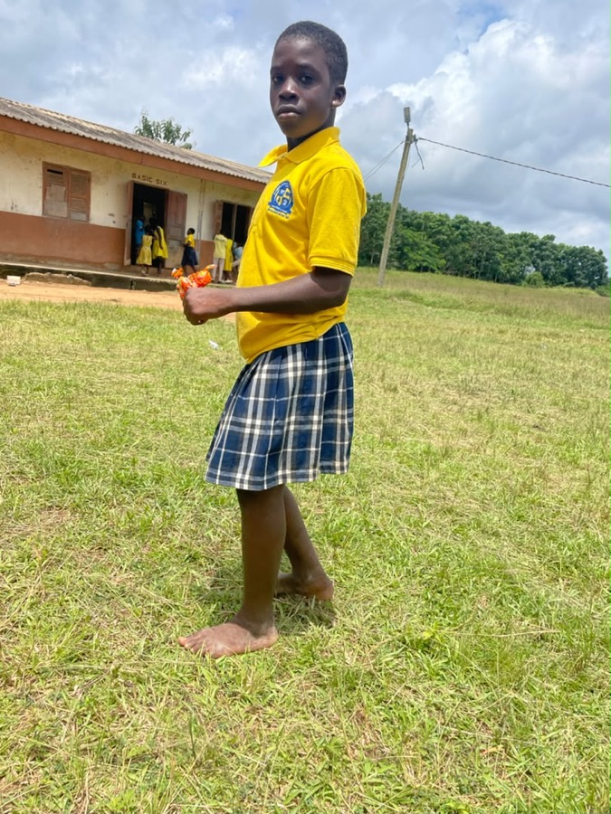 Student standing barefoot outside her school
